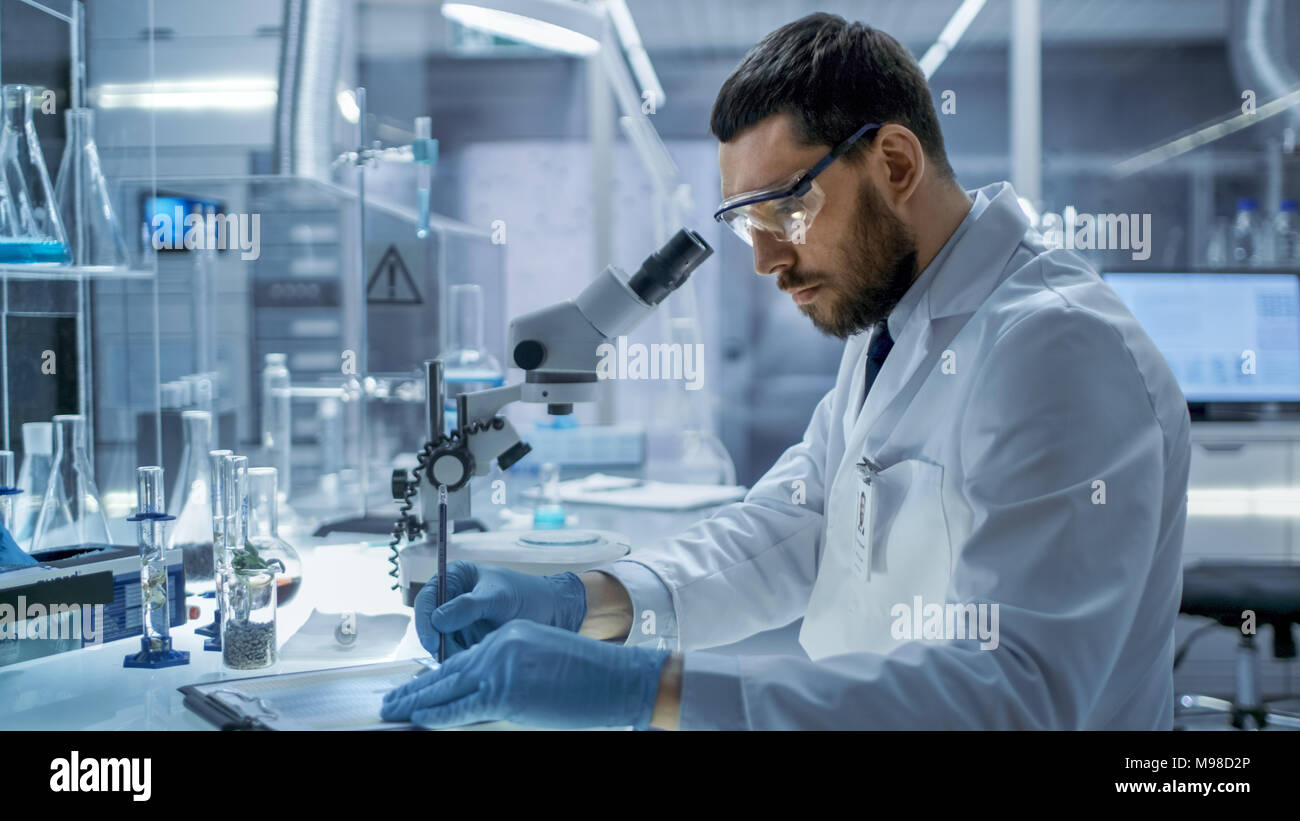 In a Modern Laboaratory Research Scientist Writes Down His Experiment Observations. Stock Photo