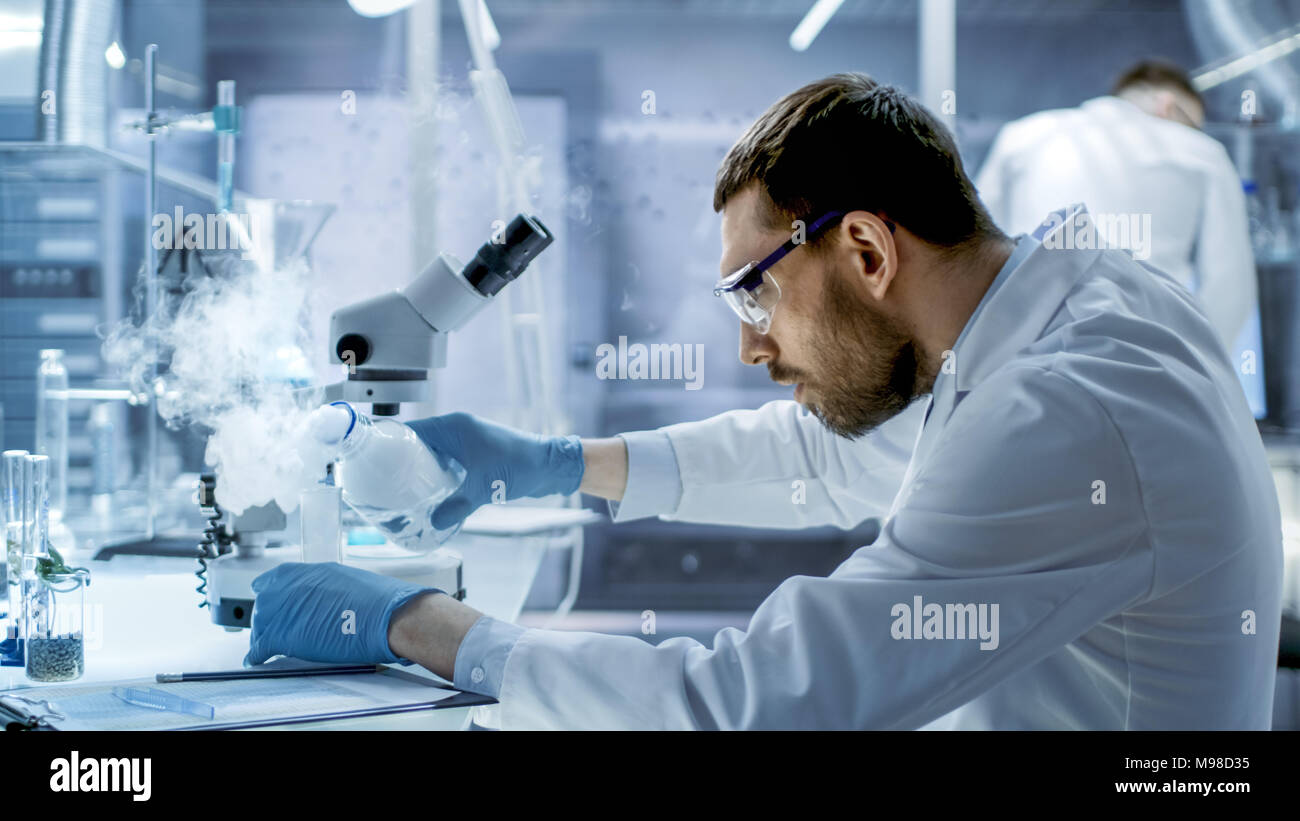 In a Chemical Research Laboratory Scientist Mixes Smoking Compounds in Beakers. Stock Photo