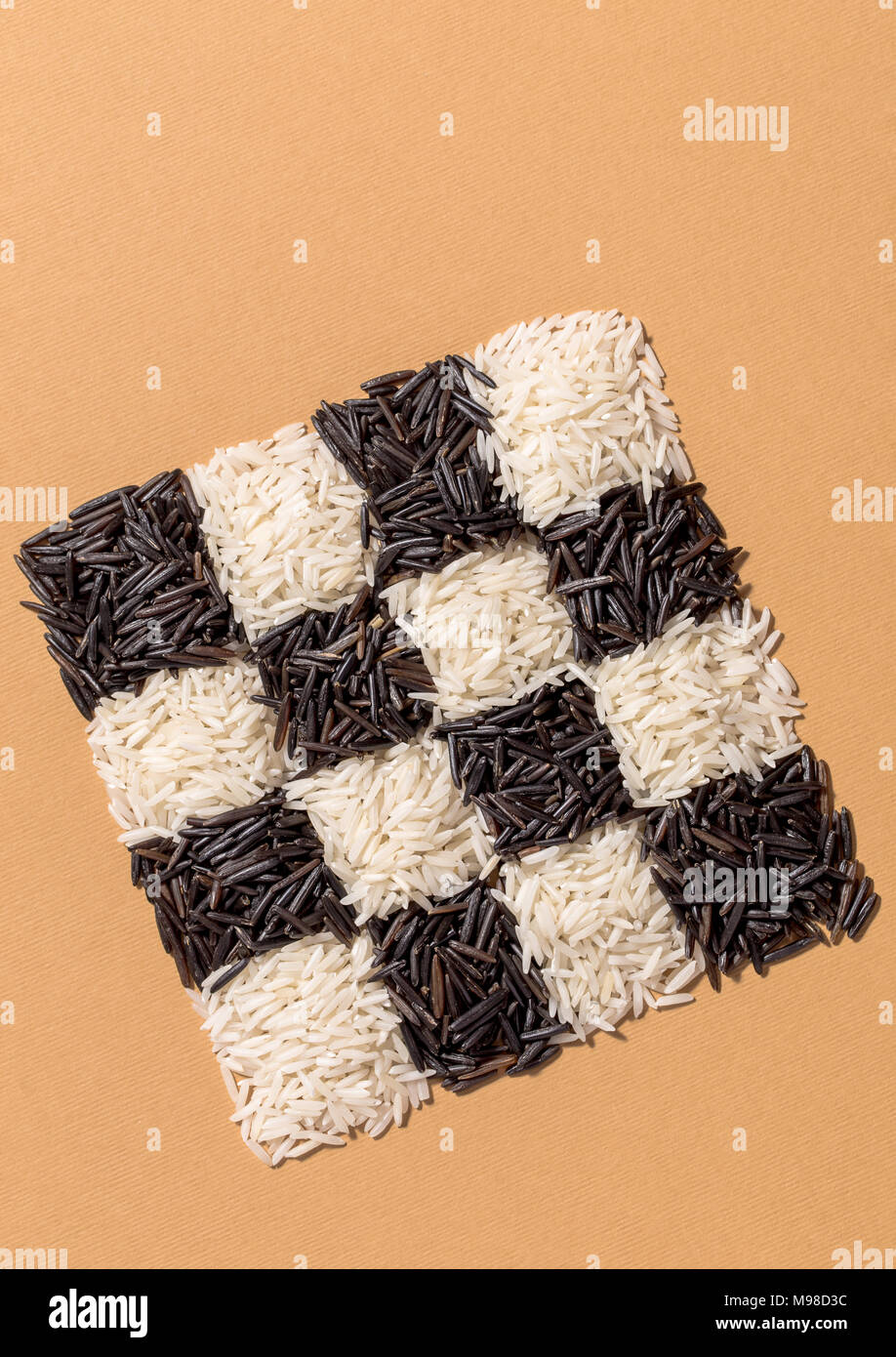 Black and white rice in a checkerboard pattern on orange background top view Stock Photo