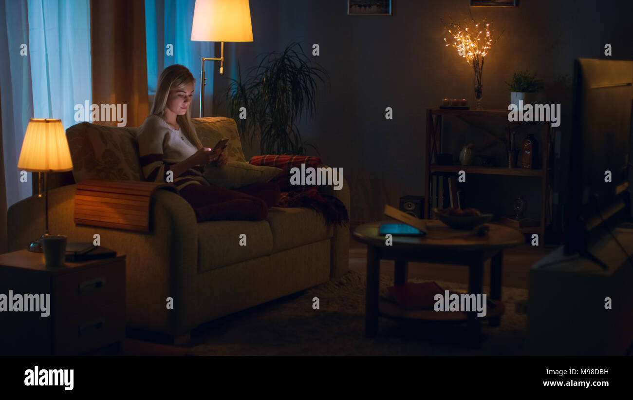 In the Evening Beautiful Young Woman Relaxes on a Couch in Her Cozy ...
