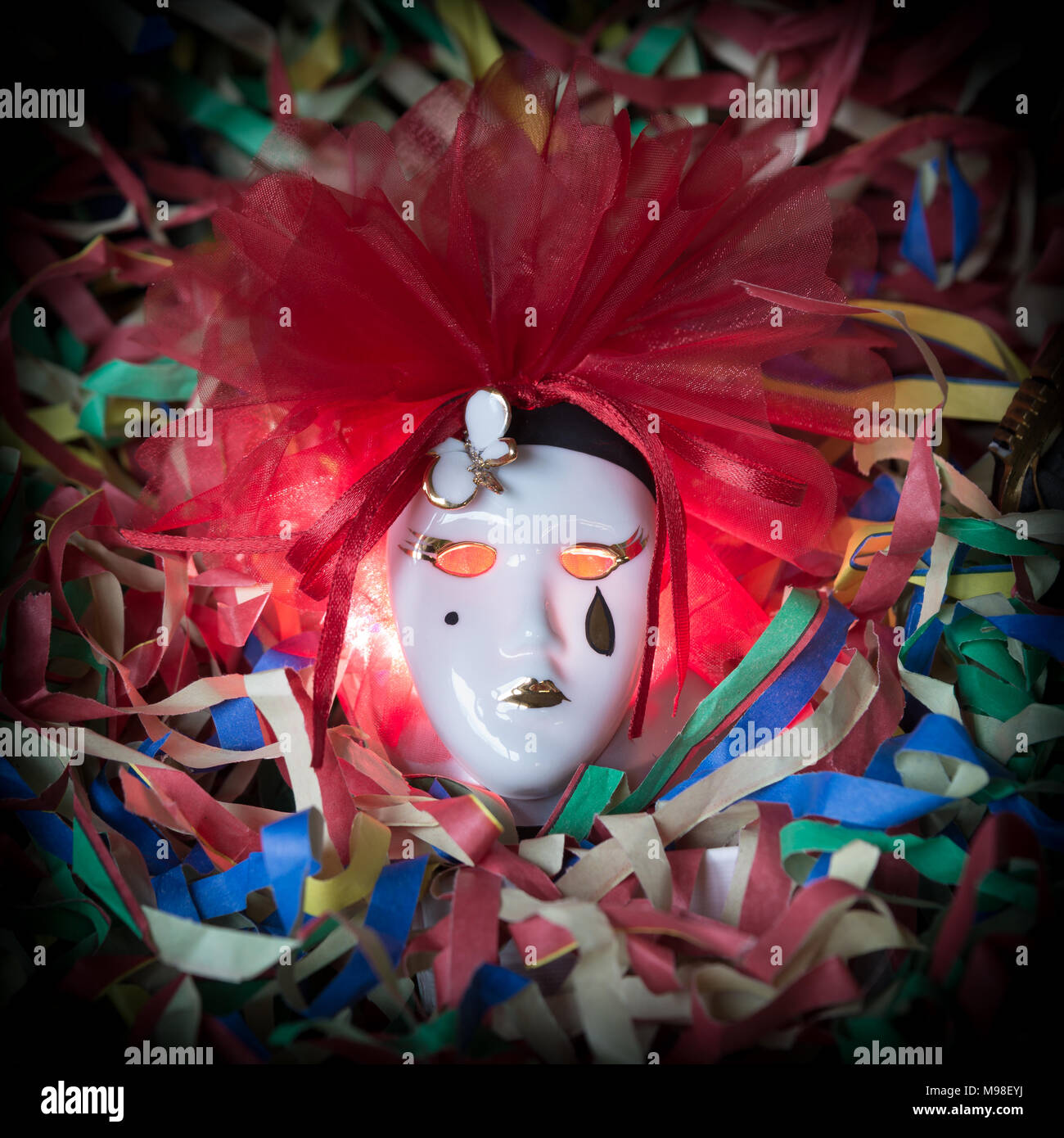 Close-up of Pierrot carnival mask on a background of colored streamers Stock Photo