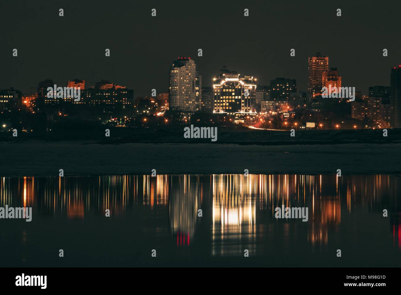 Night city view with lots of lights and its reflection in a river water ...