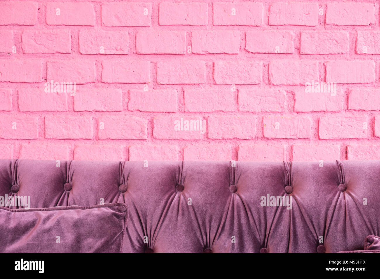 Purple luxury sofa at pastel pink painting on brick wall,Leave space for adding your design or use as background for advertise your product. Stock Photo
