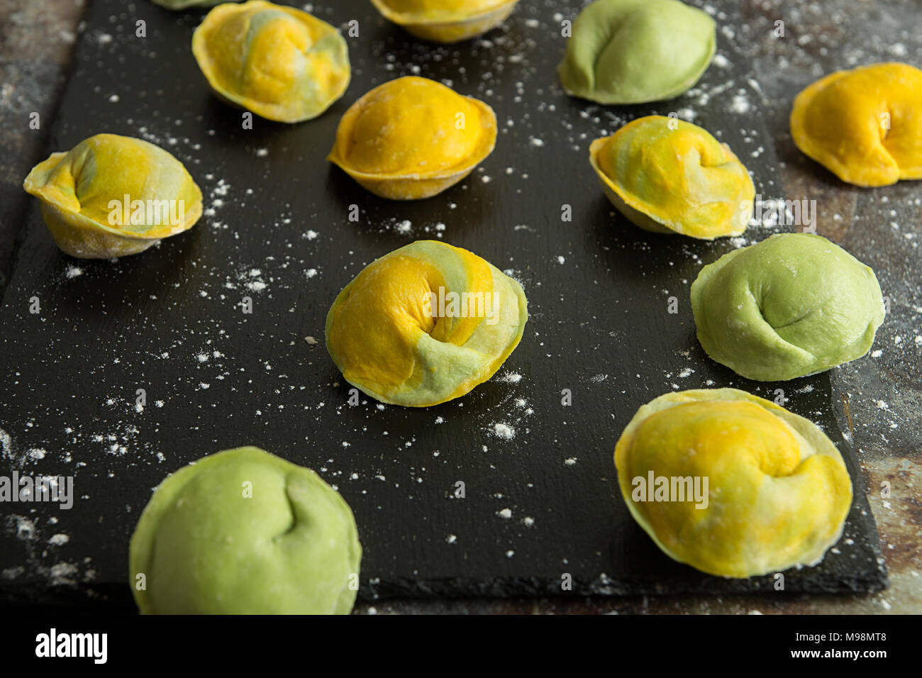Homemade raw dumpling, yellow and green colors, traditional East European food before boiling. Top view. Stock Photo