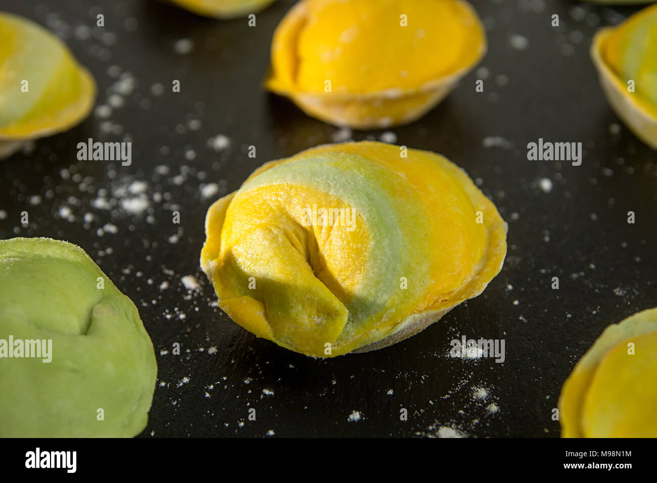 Homemade raw dumpling, yellow and green colors, traditional East European food before boiling. Close up Stock Photo
