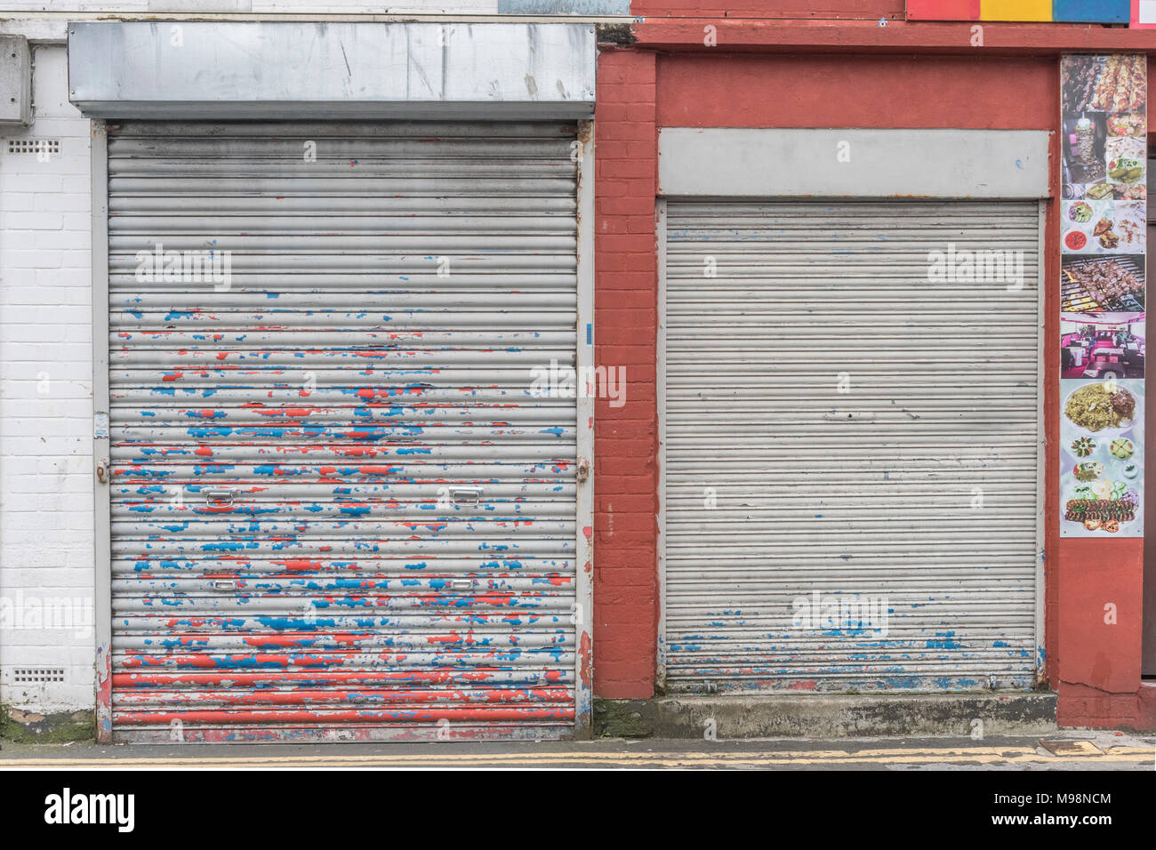 Battered closed roller shutter door with paint peeling off. Metaphor recession, high street closures, vacant shops. Obstructed or obstruction concept. Stock Photo