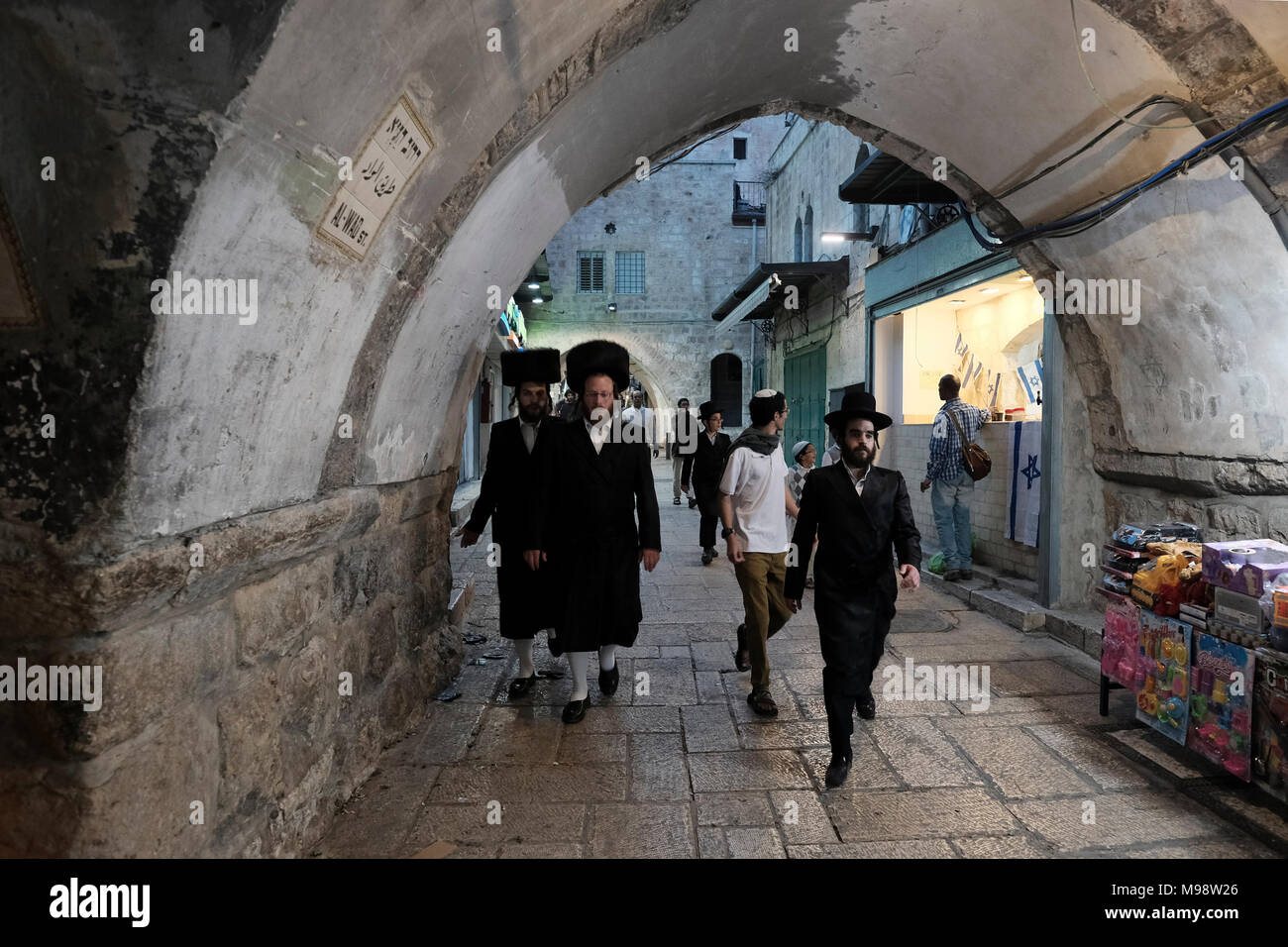 Orthodox religious Jews walk through in Al Wad street which Israelis call Haggai in the Muslim Quarter, old city of Jerusalem Israel Stock Photo