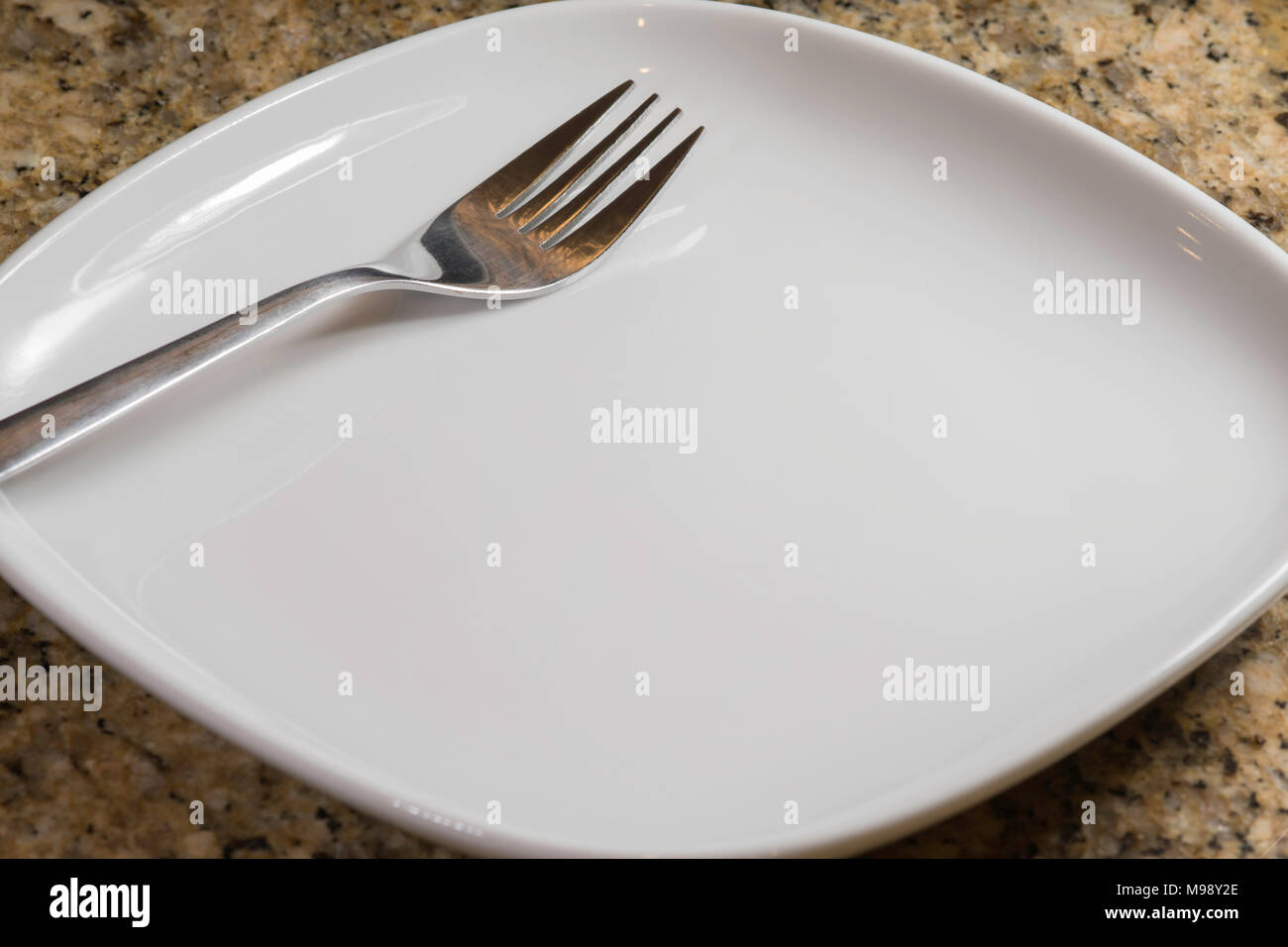 empty square white plate with a fork on the diagonal Stock Photo