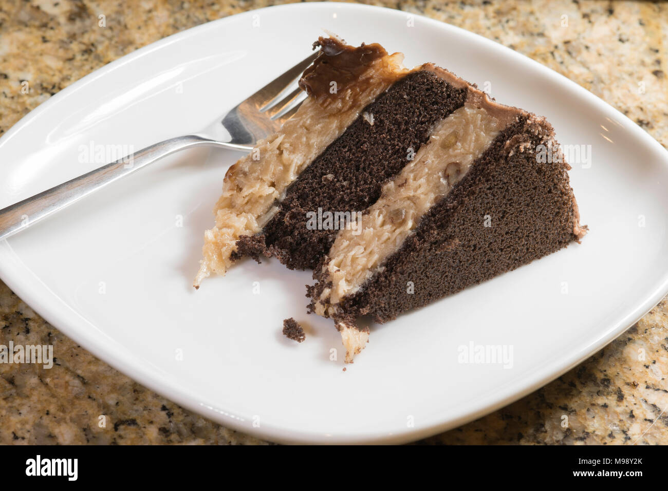 piece of German chocolate cake on a white plate with a fork Stock Photo