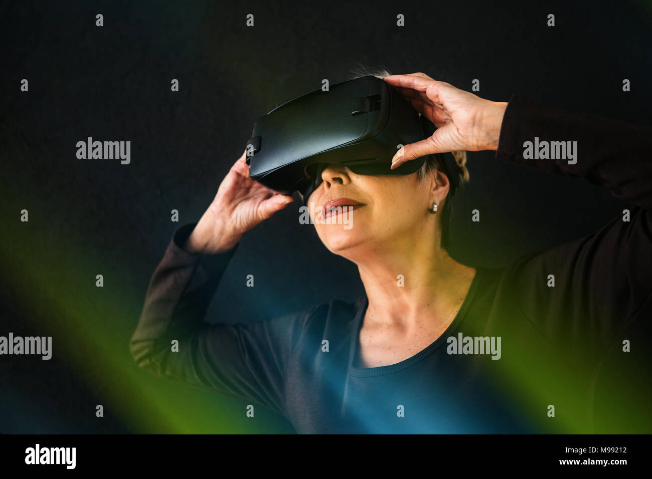 An elderly woman in virtual reality glasses. An elderly person using modern technology Stock