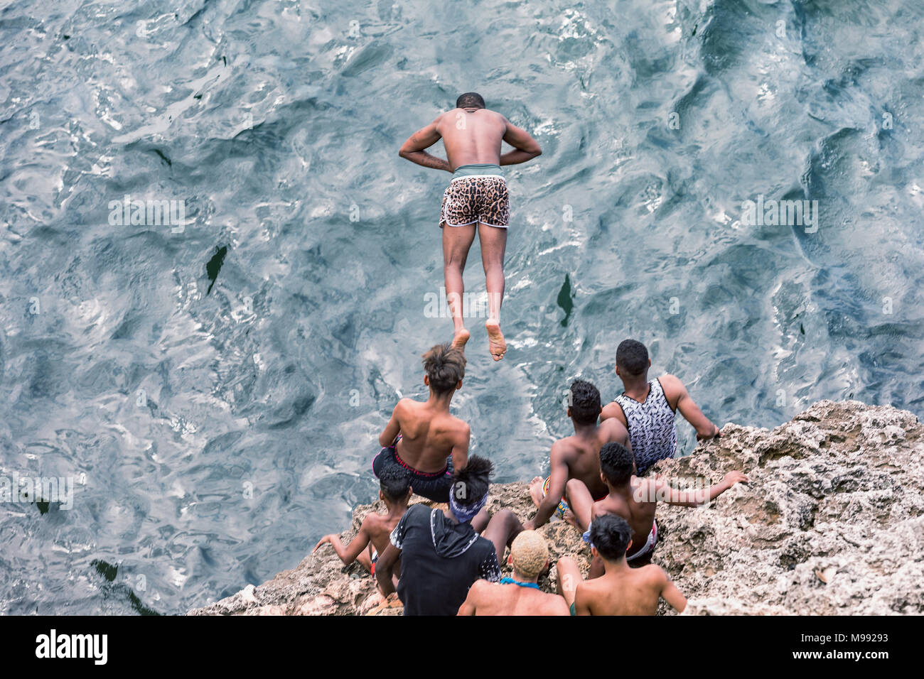 The boys from Havana are jumping from the rocks into the sea. Cuba, Havana. Jump, danger. Young Cubans gather jumping from rock to the sea. Stock Photo