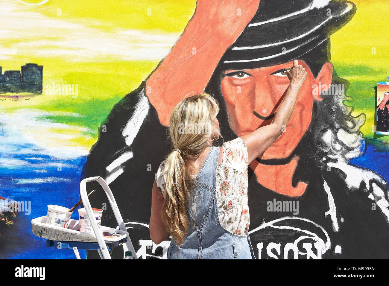 Young female artist painting a large mural at the Indian wells art festival in Palm Desert California Stock Photo