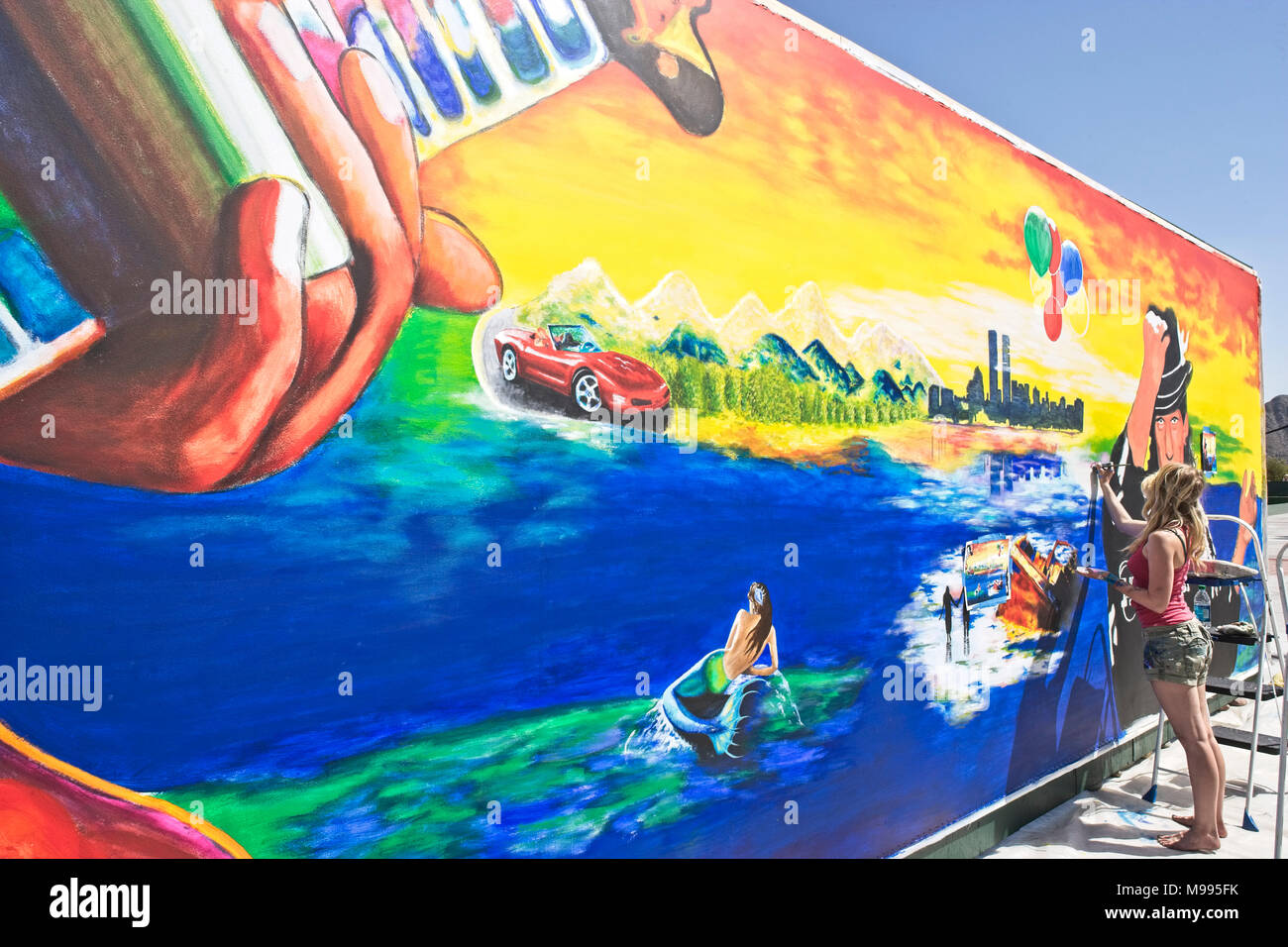 Young female artist painting a large mural at the Indian wells art festival in Palm Desert California Stock Photo