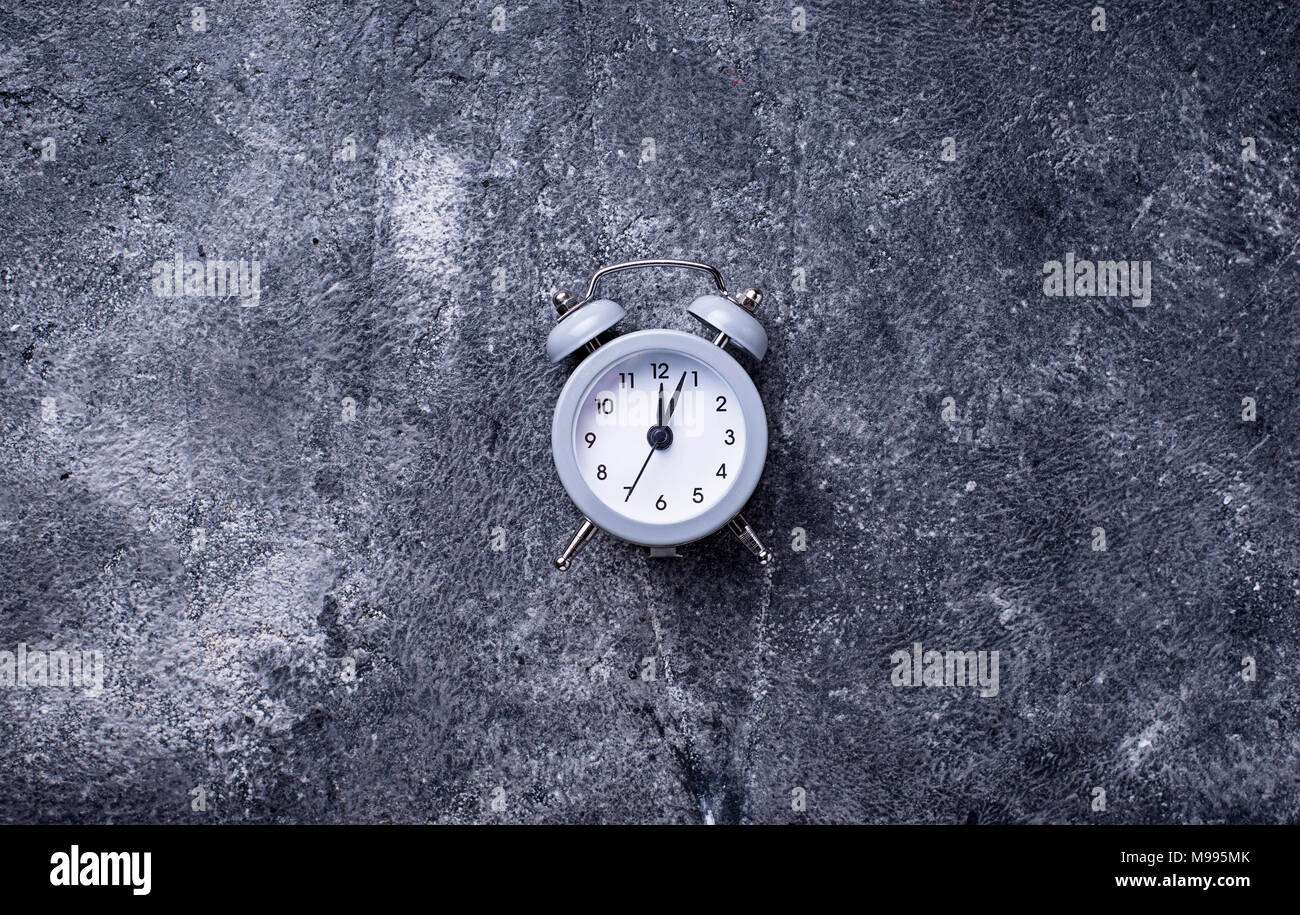 Grey vintage alarm clock on concrete table Stock Photo