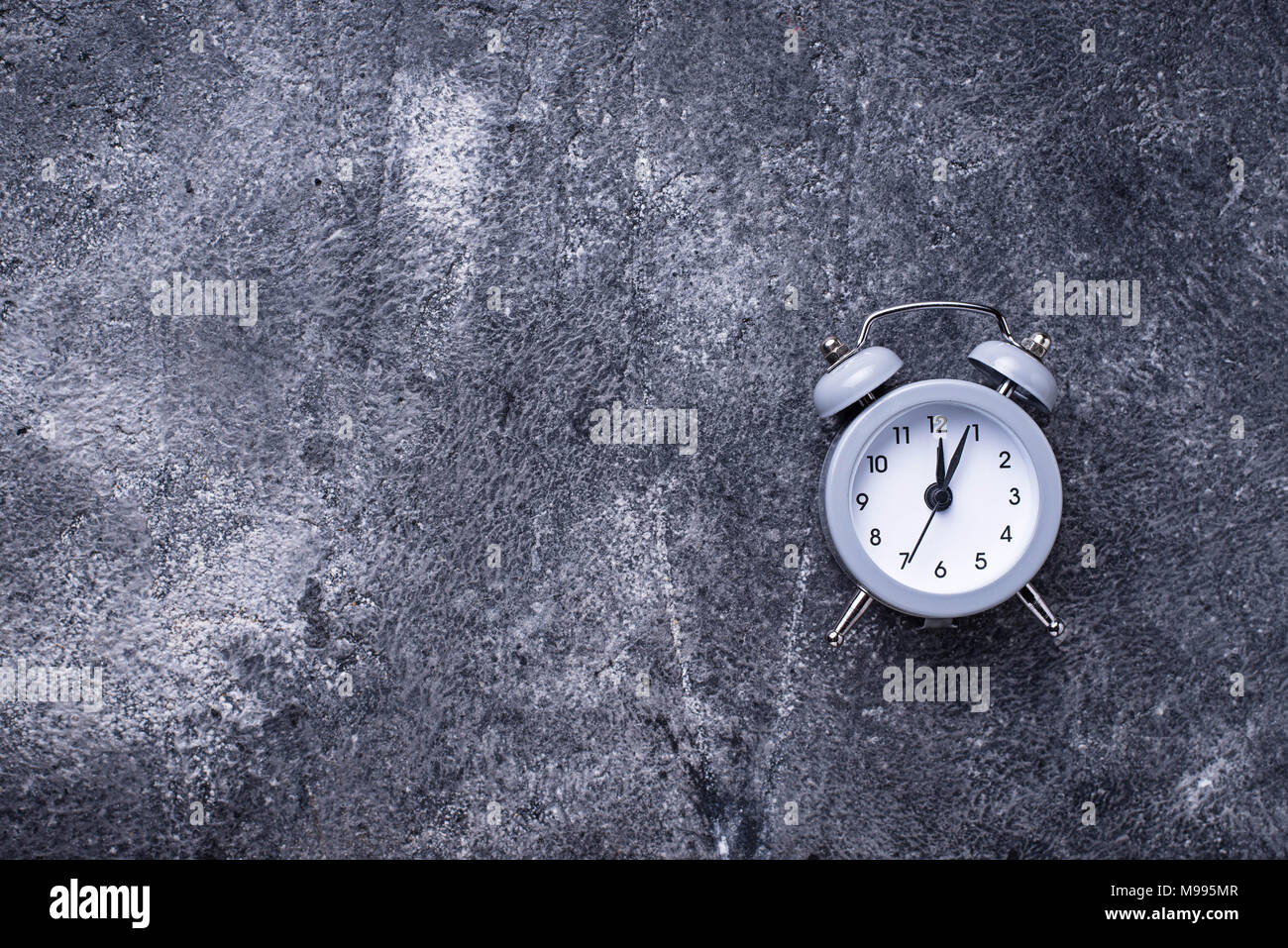 Grey vintage alarm clock on concrete table Stock Photo