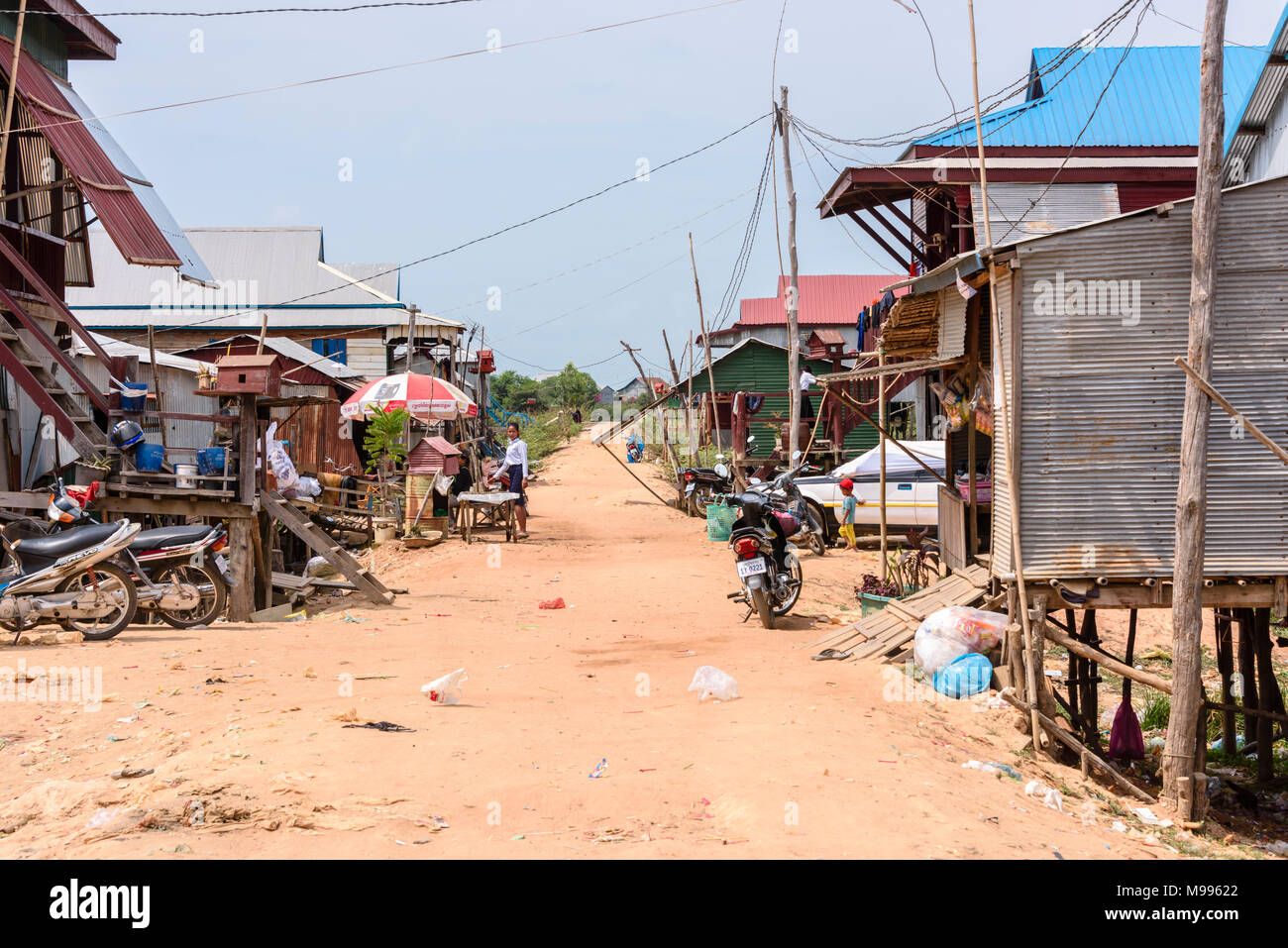 Houses in a poor, rural village with a dirt track road in Cambodia