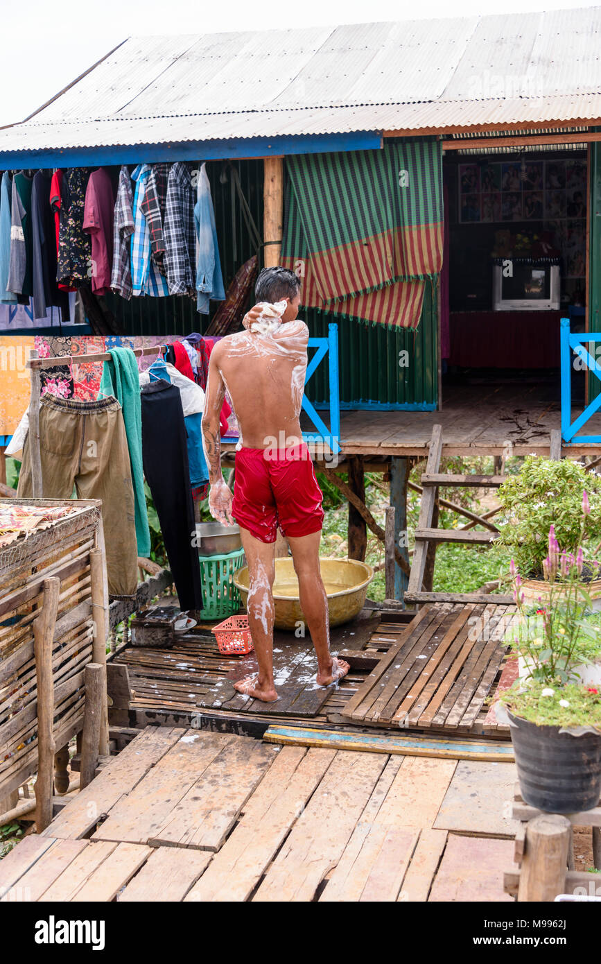 A Cambodian man washes outside his house in a poor, rural village in