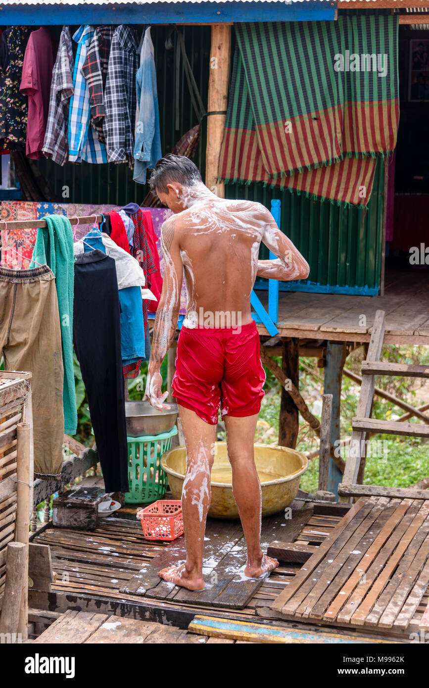 A Cambodian man washes outside his house in a poor, rural village in
