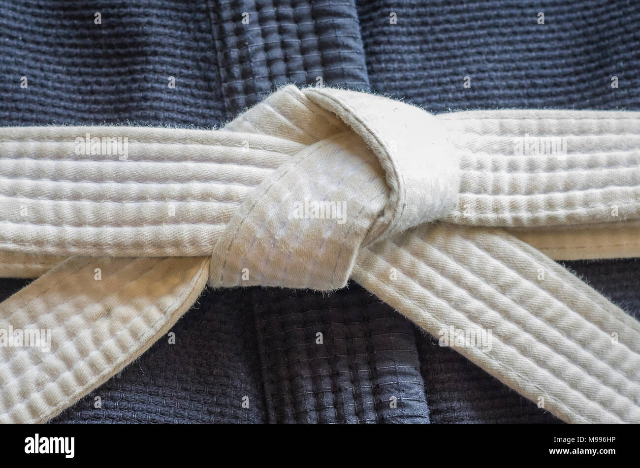 White belt of Brazilian JiuJitsu with four degrees, tied in the kimono, knot of belt Stock