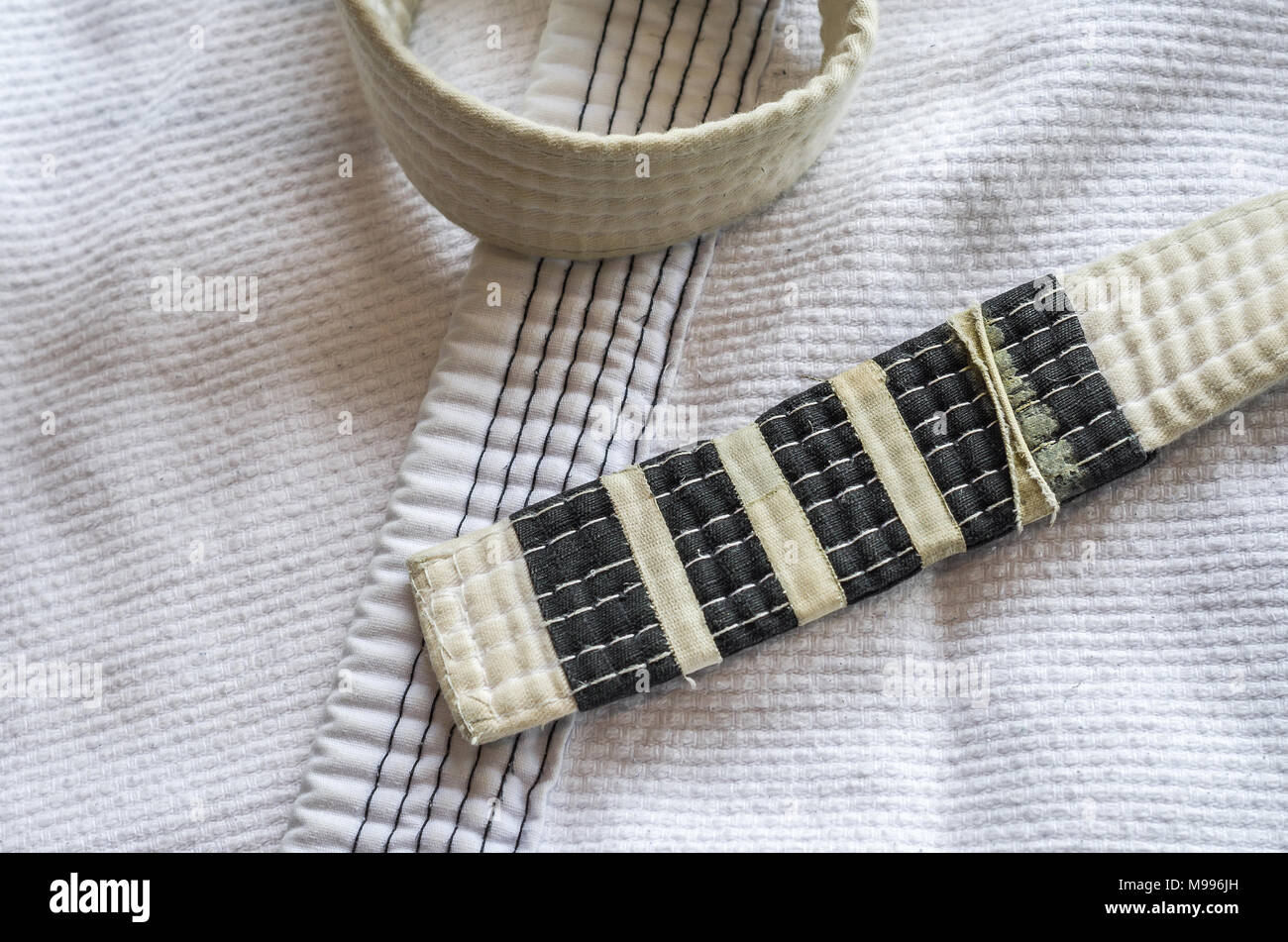 White belt of Brazilian JiuJitsu with four degrees, on top of the