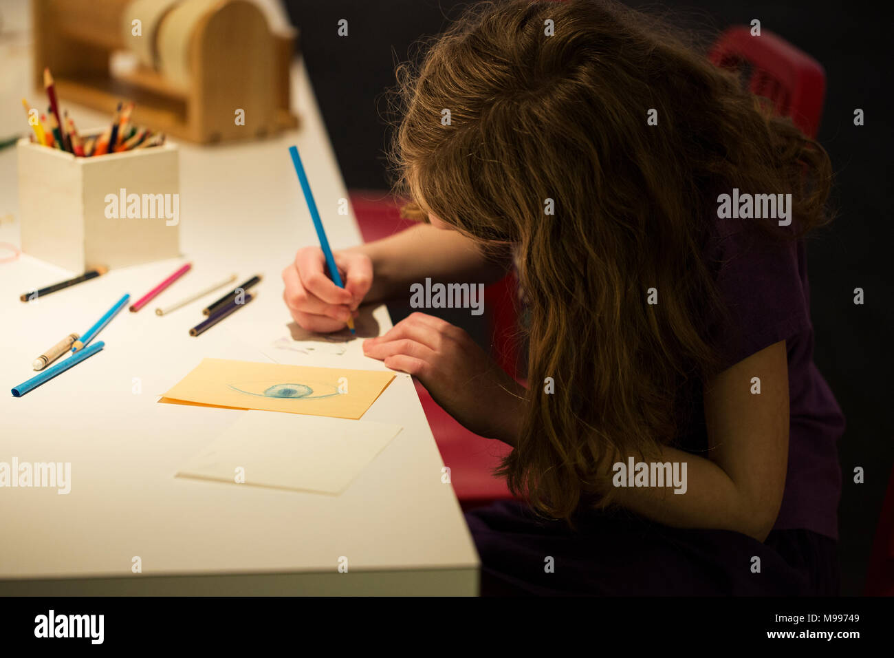 School age child (girl) drawing an eye with colored pencil Stock Photo