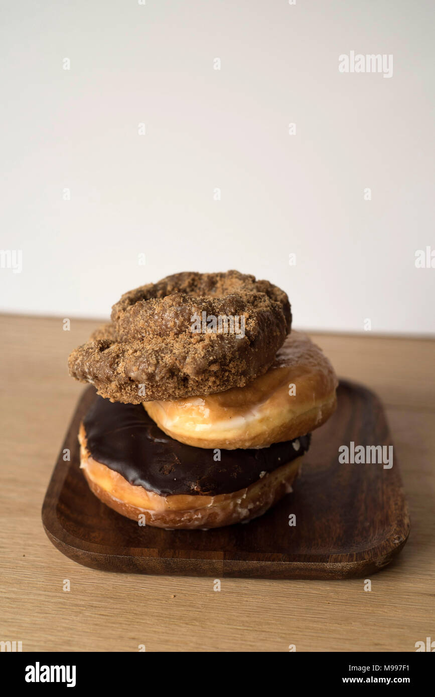 Donuts Stacked on A Wooden Plate in Front of A Light Background Stock Photo