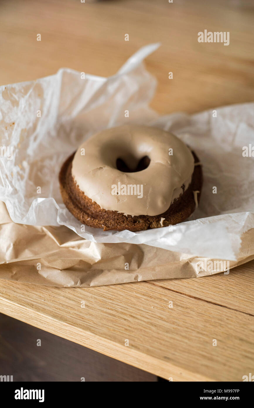 Gluten-Free Doughnut Unwrapped on Light Wood Table Stock Photo