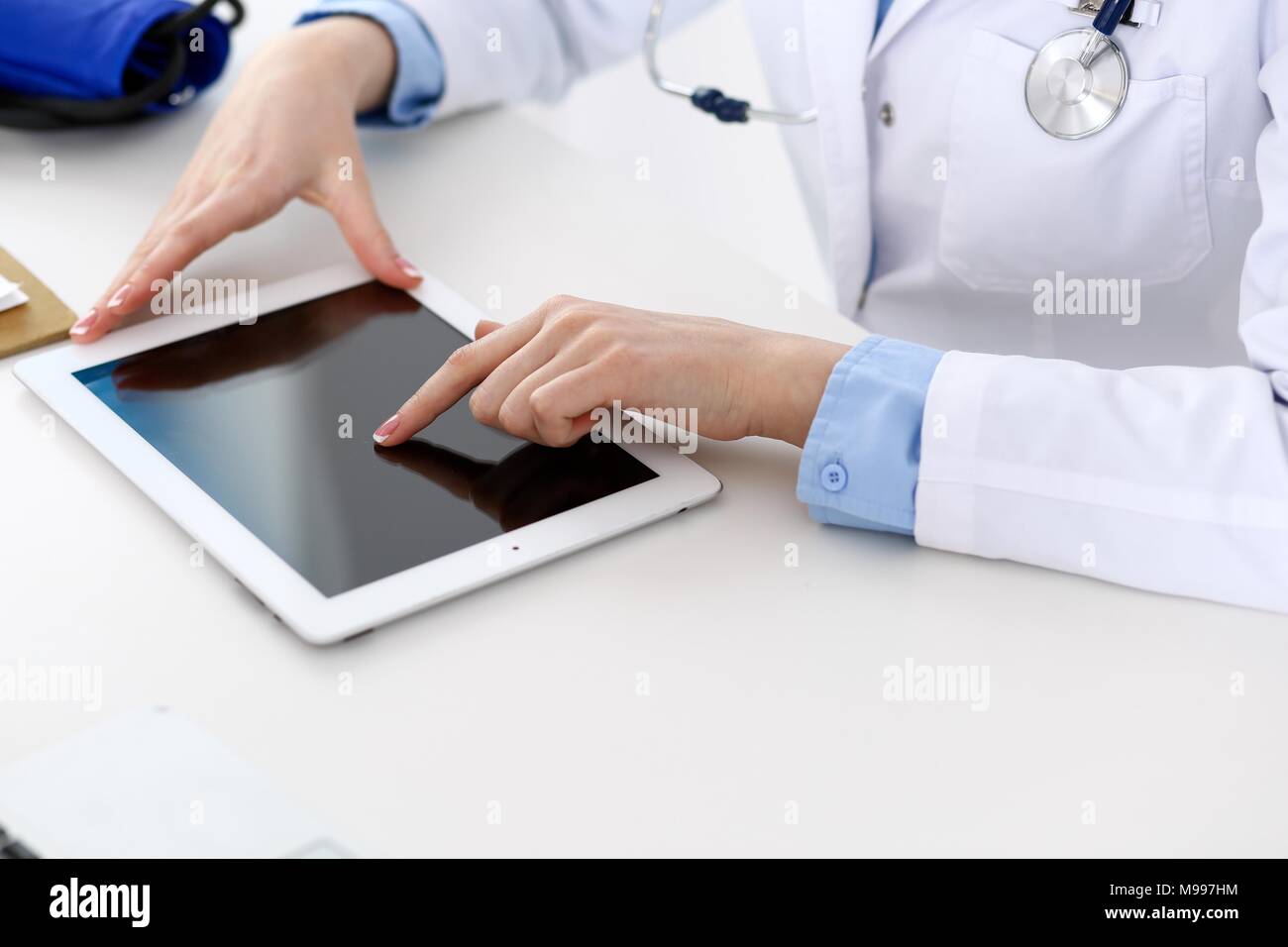 Woman Doctor Using Tablet Computer While Sitting At The Desk In
