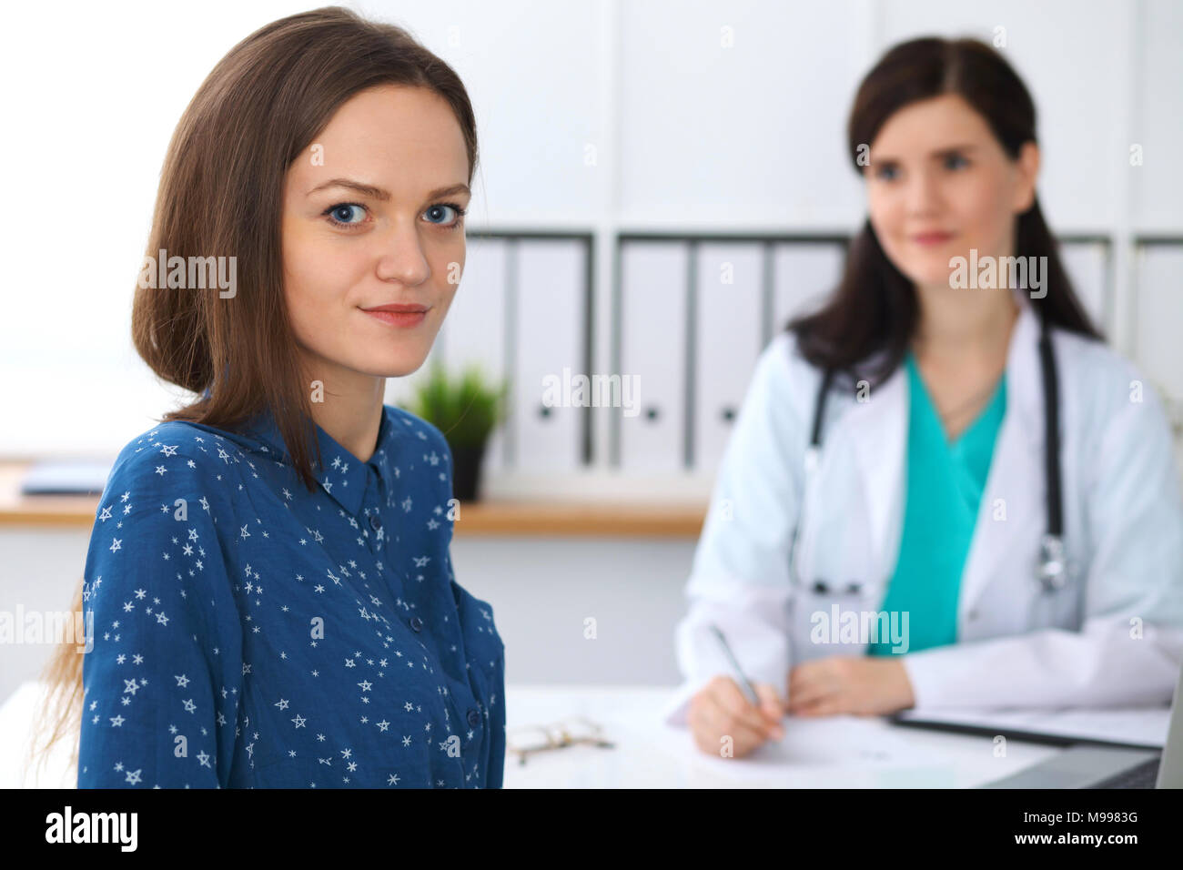 Doctor and patient having a talk while sitting at the desk. Focus on ...