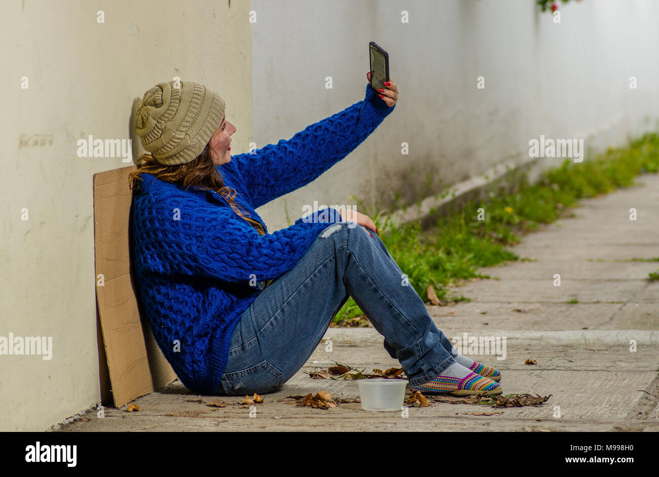 Outdoor view of homeless woman begging on the street in cold autumn ...