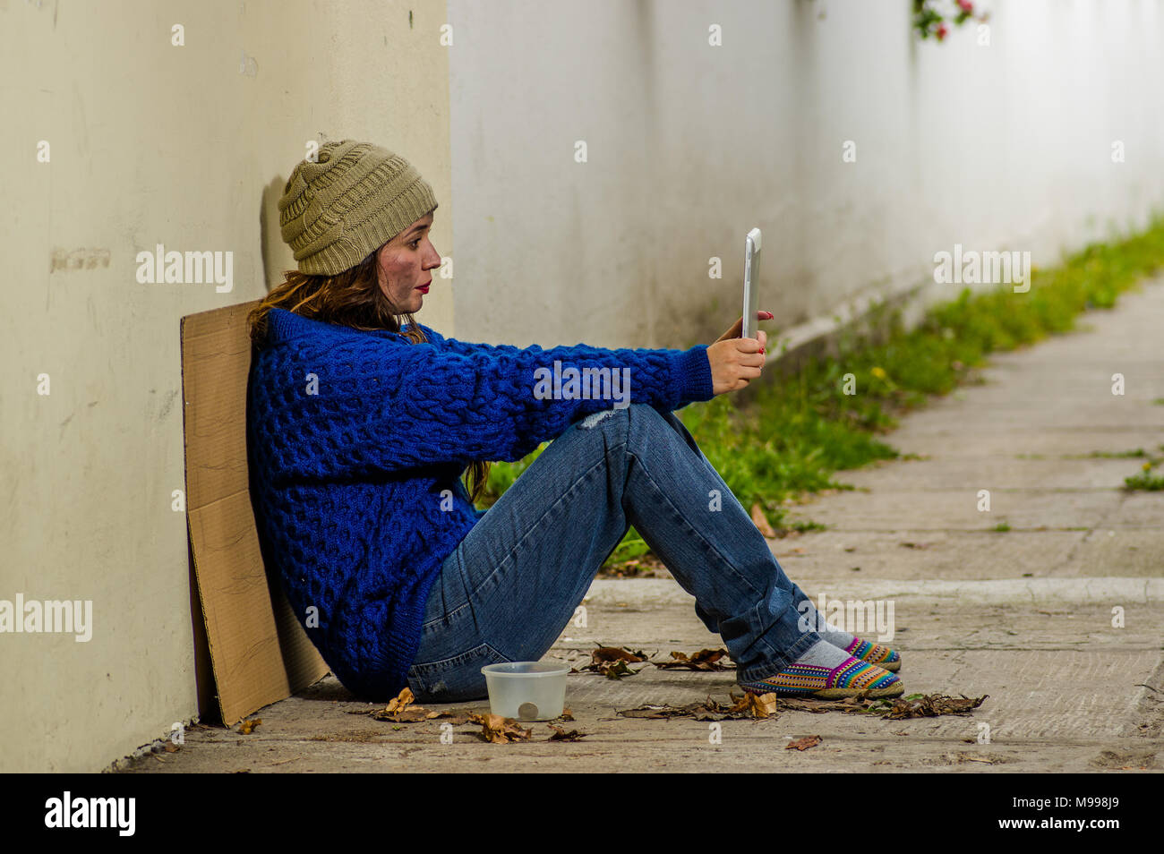 Outdoor view of homeless woman begging on the street in cold autumn ...