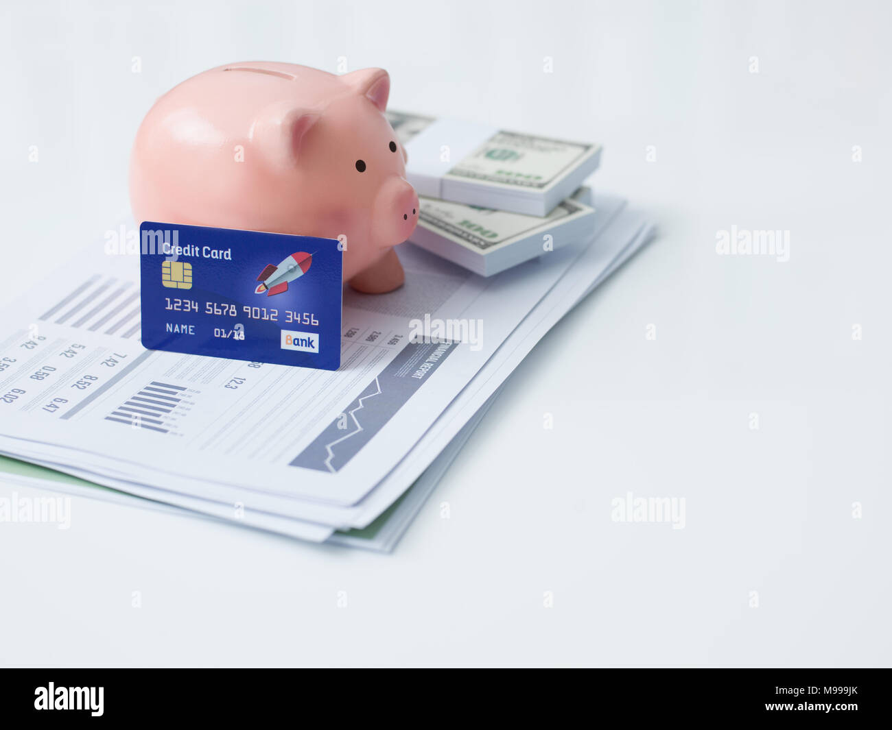 Piggy bank, credit card, cash money and financial report on a office desktop: savings, investments and bank deposit concept Stock Photo