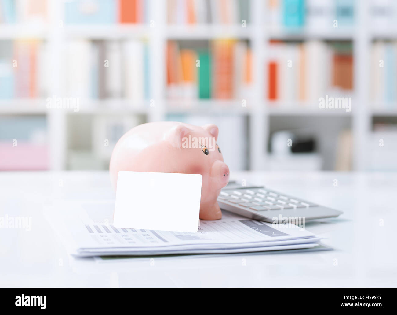Piggy bank, credit card, calculator and financial report on a office desktop: savings, investments and bank deposit concept Stock Photo