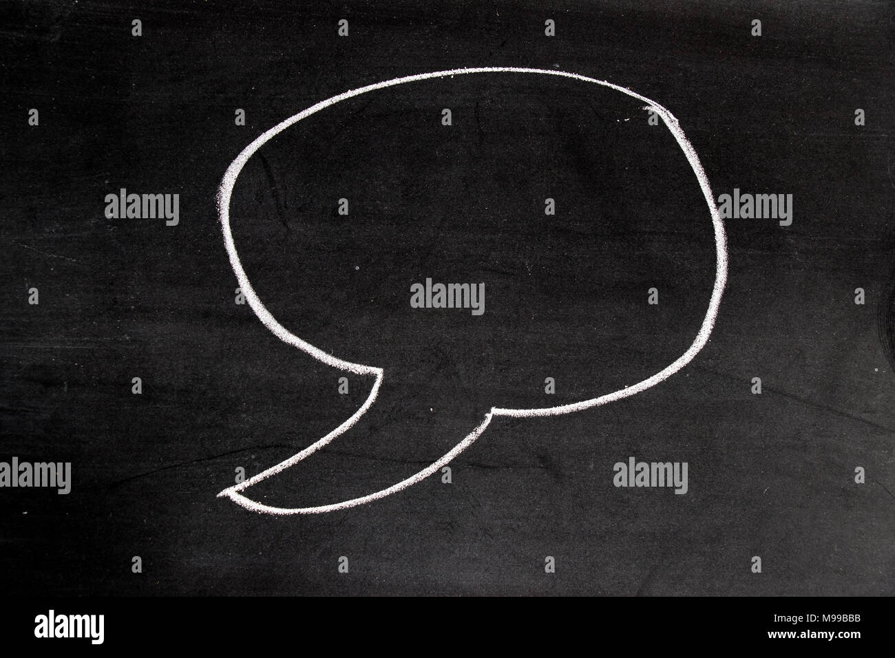 White color chalk drawing as blank speech bubble shape on blackboard ...