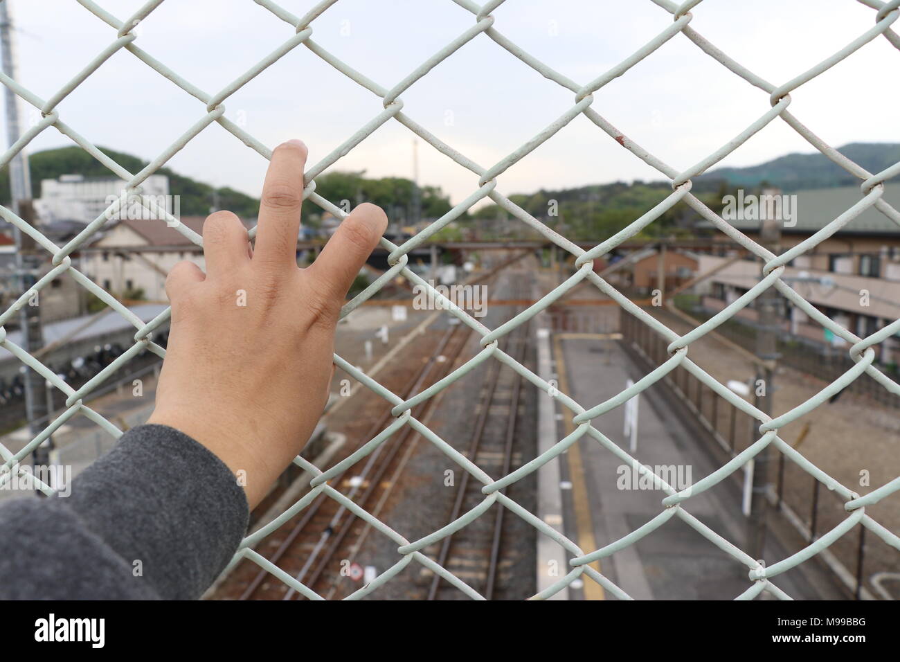 Man grasp the bar of cage with the defocused of city background Stock Photo