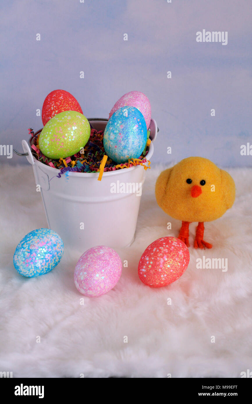 white bucket of Easter Eggs in a vertical format with a yellow chick on the side of the bucket with a clouds background Stock Photo