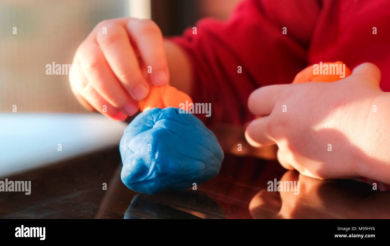 plasticine hands of the baby play with modelling clay playdought Stock Photo