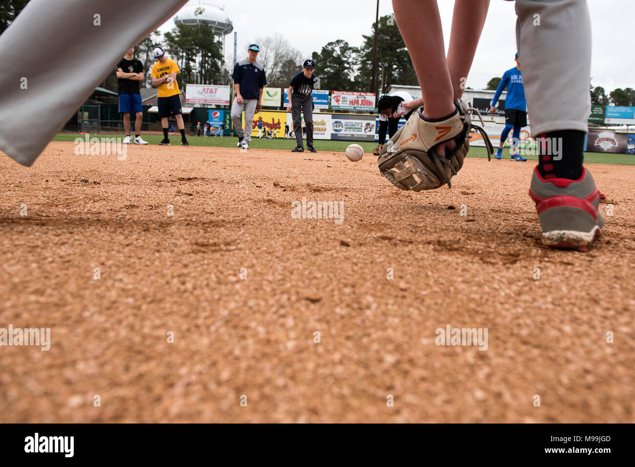 Kids roll baseballs to each other as fielding practice during the kids