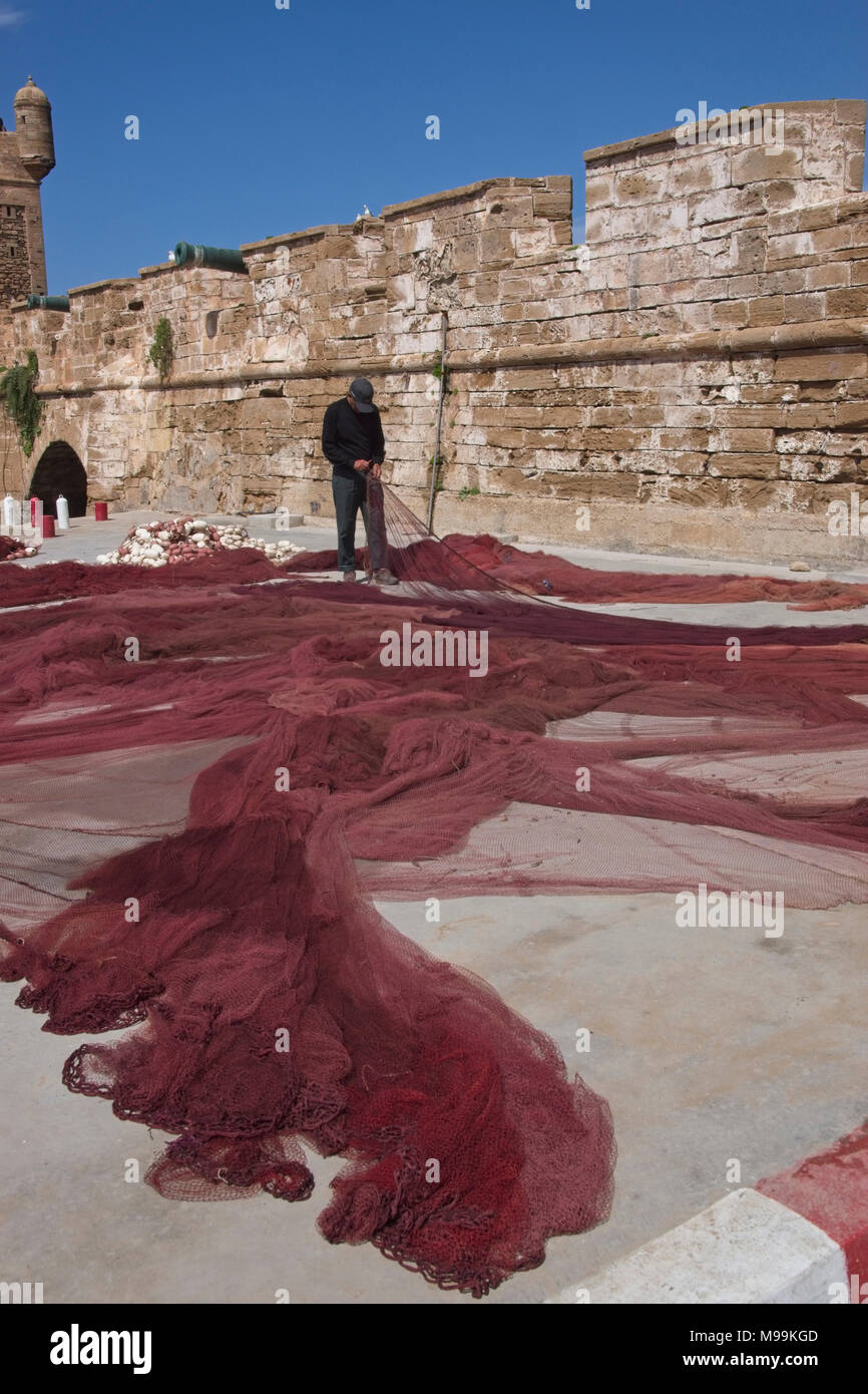 Repairing fishing net ashore. Stock Photo