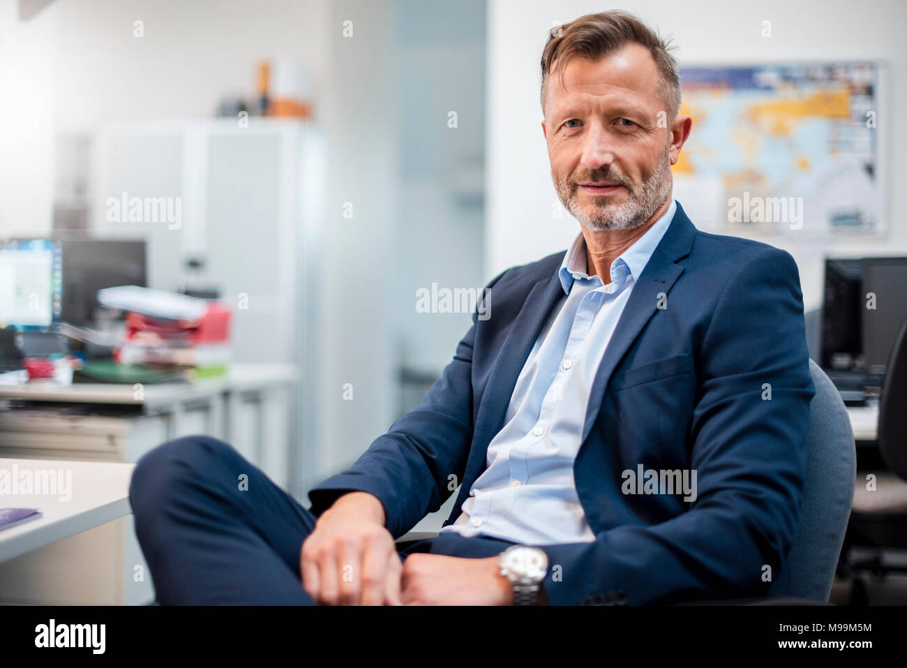 Portrait of confident mature businessman sitting at desk in office Stock Photo