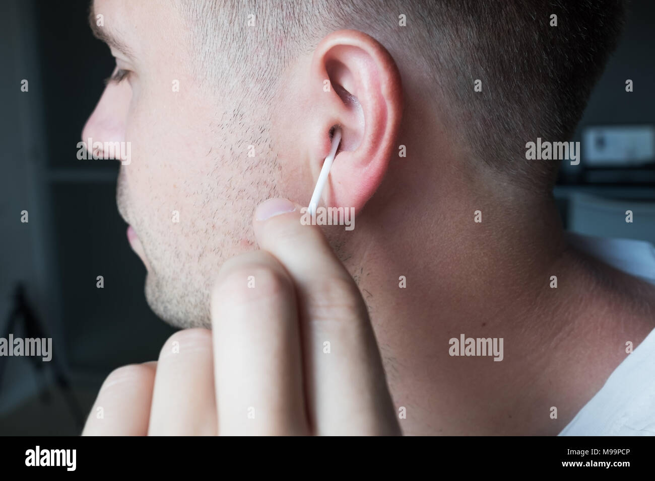 Close up shot of caucasian man cleaning his ears Stock Photo