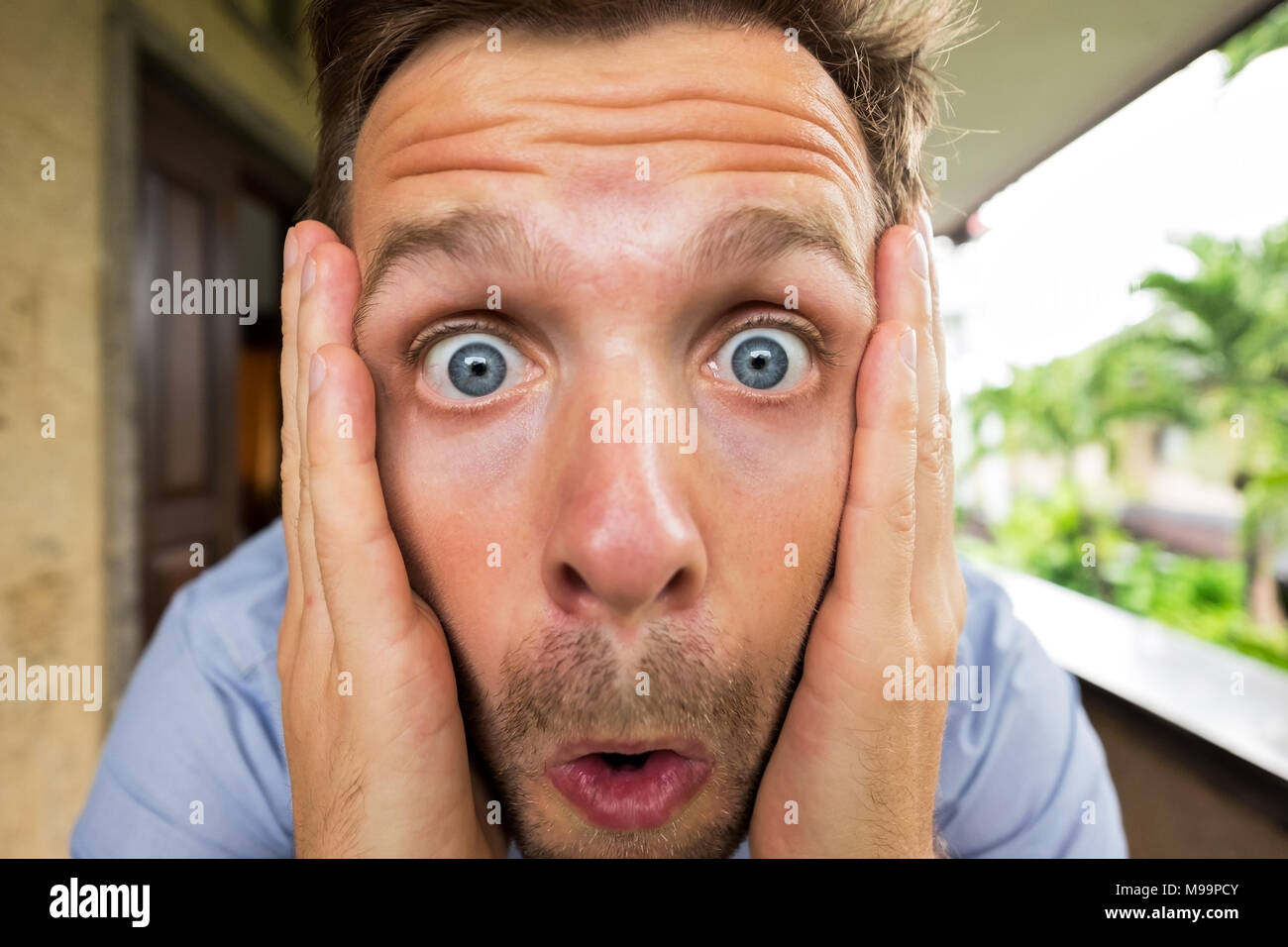 Panic man is shocked. His face is close to camera. He is opening his mouth in surprise Stock Photo