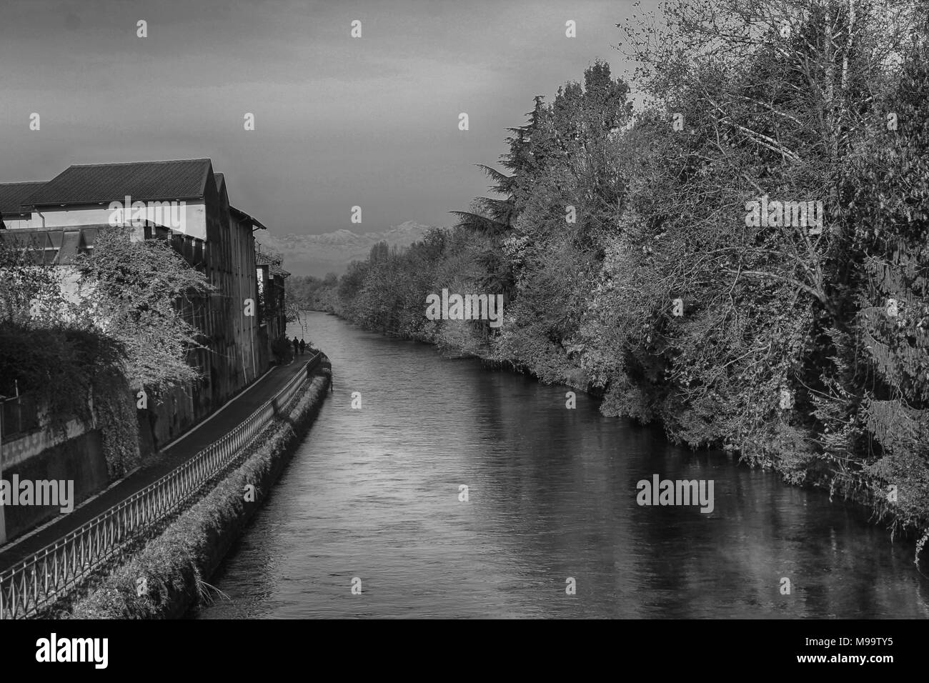 Water Canal (channel) and reflections of trees and buildings in Robbecoo sul Naviglio, Italy Stock Photo