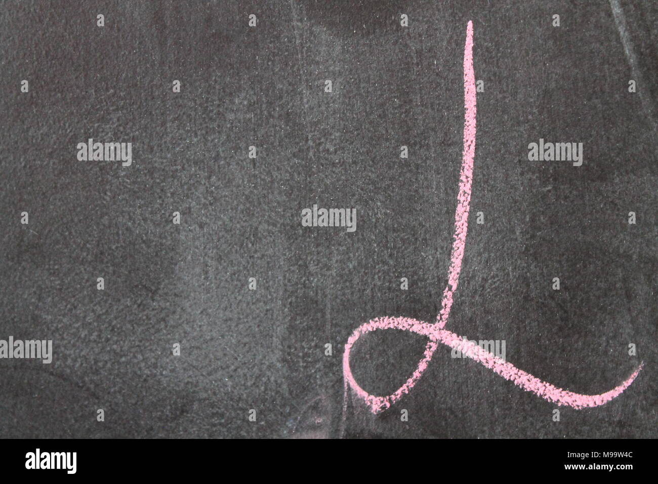 Pink letters on a dark background. Jumbled arrangement of different sized writen with chalk letters of the alphabet. Colour raised Latin letters in pe Stock Photo