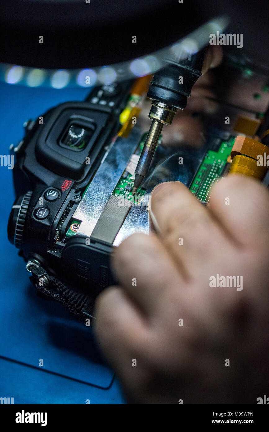 Reparing electronics devices, hands and tools, mobiles and computers. Nikon reparing Stock Photo