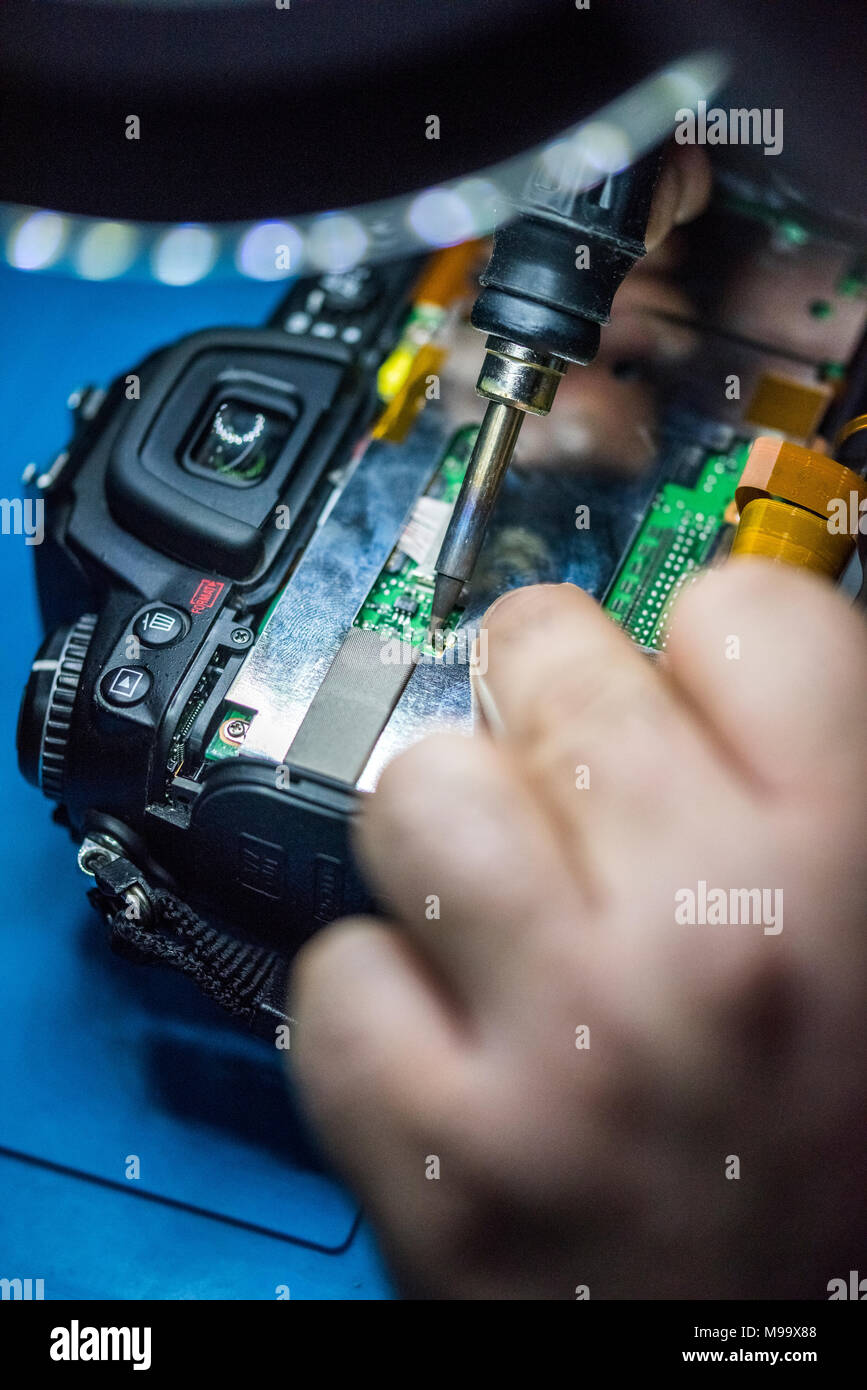 Reparing electronics devices, hands and tools, mobiles and computers. Nikon reparing Stock Photo