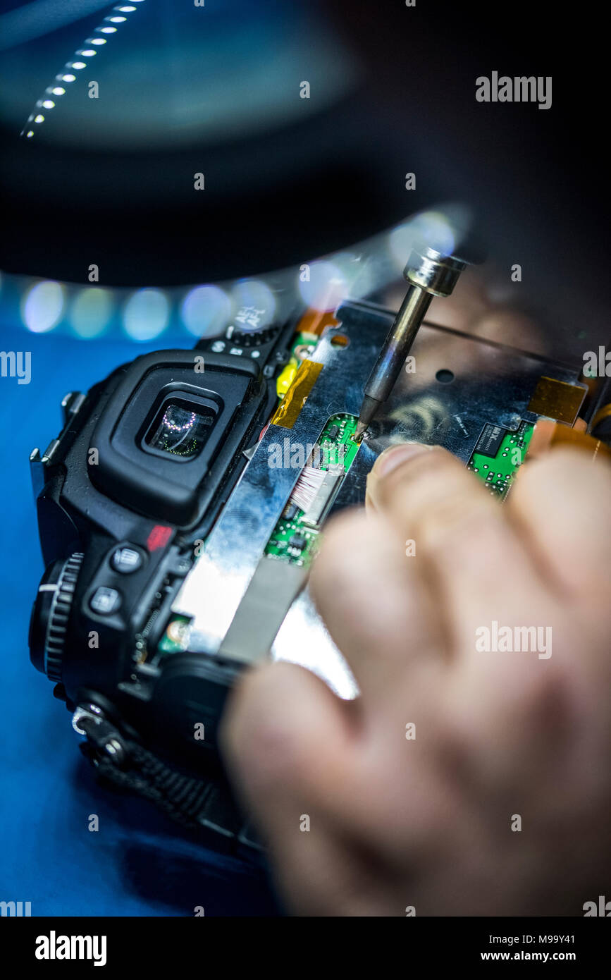 Reparing electronics devices, hands and tools, mobiles and computers. Nikon reparing Stock Photo