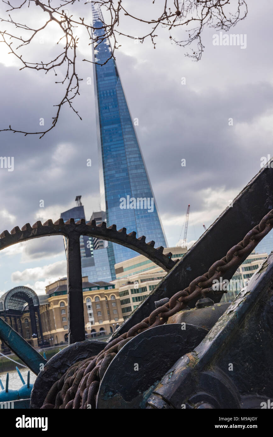 A different or unusual viewpoint or angle of the shard in central London offices. Old mechanical industrial crane by the side of the river thames. Cit Stock Photo