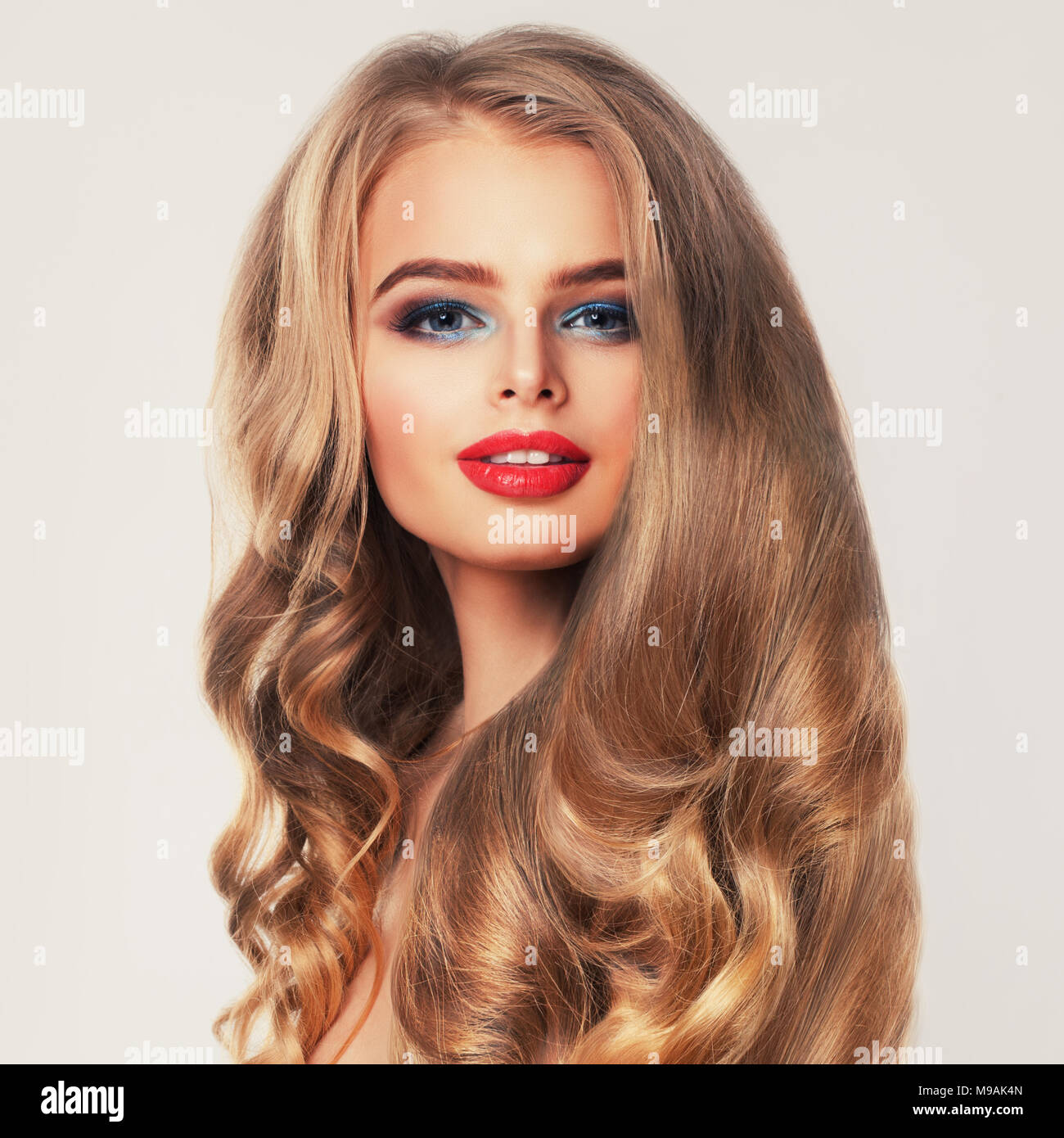 Healthy Woman with Long Blonde Hair and Makeup. Permed Hairstyle Stock Photo