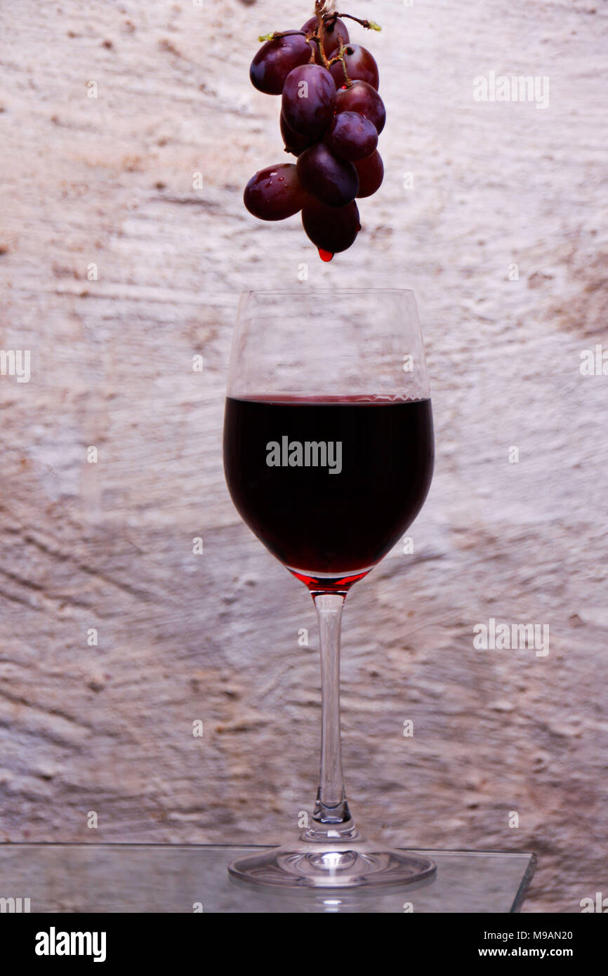 Hanging grapes with red wine dropping into a glass Stock Photo Alamy